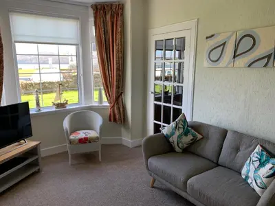a living room with a couch and a tv and a chair at Eilean View in Lamlash