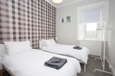 two beds in a room with a checked wall at The Warwick Apartment in Greenock