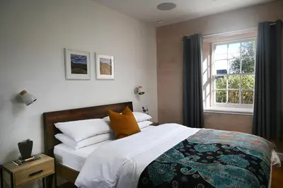a bedroom with a bed with white sheets and a window at The Auld Kirk & Spa in Stirling