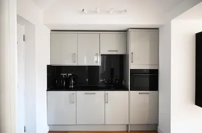 a kitchen with white cabinets and black appliances at The Auld Kirk & Spa in Stirling