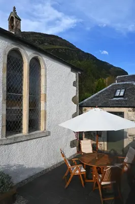 a table and chairs with an umbrella in front of a building at The Auld Kirk & Spa in Stirling