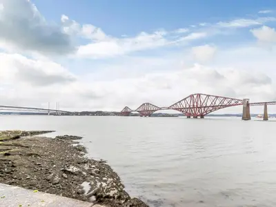 a bridge over the water with a cloudy sky at Forth Reflections in Queensferry