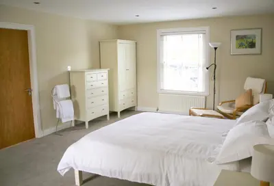 a bedroom with a white bed and a dresser and a window at Pirn Mill Self Catering Cottage in Cladich
