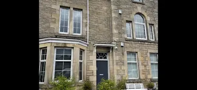 a brick building with a blue door and windows at Premier Studio B in Broxburn