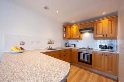 a kitchen with wooden cabinets and a counter top at Esplanade Court Holiday Apartments in Oban