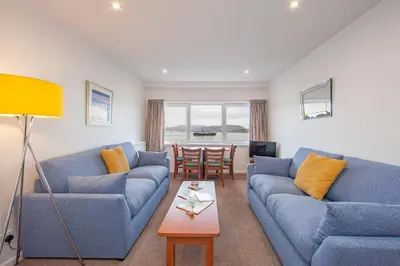 a living room with two blue couches and a table at Esplanade Court Holiday Apartments in Oban