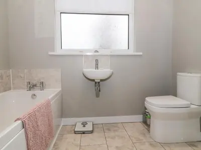 a bathroom with a sink and a toilet and a window at Honesty Cottage in Girvan