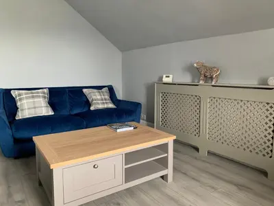 a living room with a blue couch and a coffee table at The Clachan Flat in Rosneath