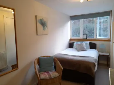 a bedroom with a bed and a mirror and a chair at Elderslie Guest House in Oban