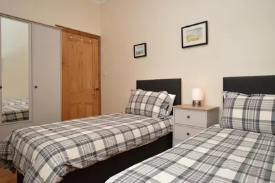 a bedroom with two beds and a mirror at Freeland Cottage in Dunoon