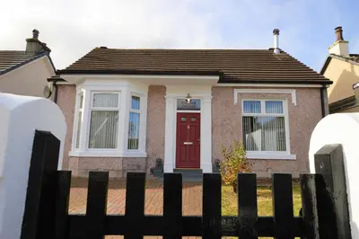a house with a red door and a fence at Freeland Cottage in Dunoon