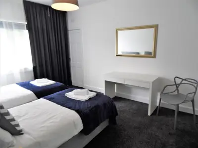 a bedroom with two beds and a desk and a mirror at Penilee Upper Apartment in Glasgow