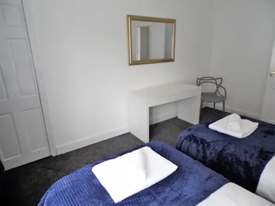 a room with two beds and a mirror and a desk at Penilee Upper Apartment in Glasgow