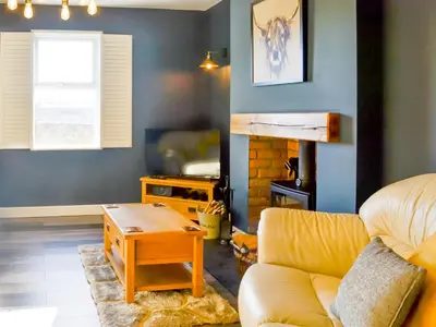 a living room with a couch and a table at Broomlands Cottage in Beattock