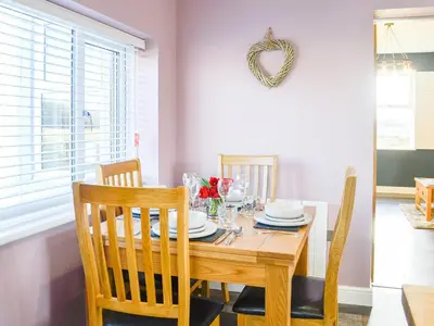 a dining room with a wooden table and chairs at Broomlands Cottage in Beattock