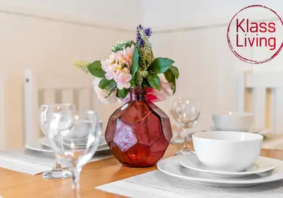 a vase with flowers in it sitting on a table at Nicol Apartment by Klass Living Airdrie in Airdrie