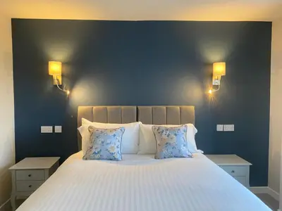 a bedroom with a large bed with blue walls at The Inn At Charlestown in Dunfermline