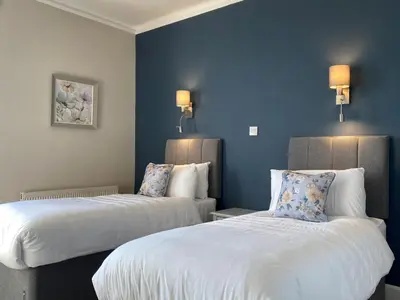 two beds in a hotel room with blue walls at The Inn At Charlestown in Dunfermline