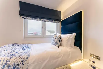 a bedroom with a bed with a blue headboard and a window at The Shore in Queensferry