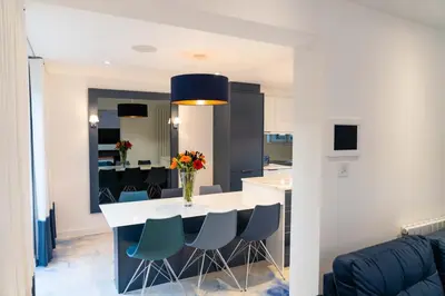 a kitchen and dining room with a white table and blue chairs at The Shore in Queensferry