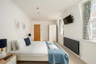 a bedroom with a bed and a tv on the wall at Queensferry Street Lane - Fantastic 2 BR City Centre Mews House with free secure parking! in Edinburgh