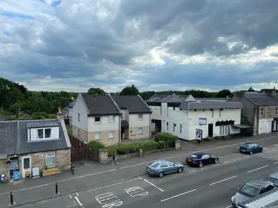 a city with cars parked on a street with houses at Premier Apartment D in Broxburn