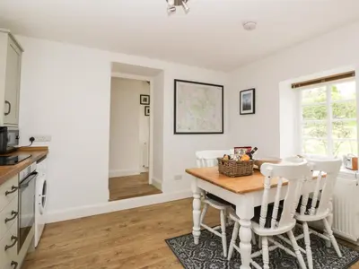 a kitchen with a wooden table and white chairs at Ellanderroch in Glasgow