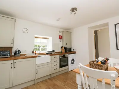 a kitchen with white cabinets and a table at Ellanderroch in Glasgow