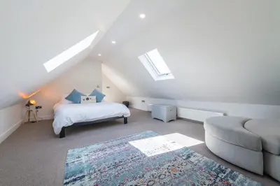 a bedroom with a bed and a couch in a attic at The Hideaway - Farm Stay with hottub, pool table and outdoor cinema in Newmilns