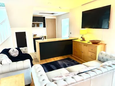 a living room with two white couches and a flat screen tv at The Hideaway - Farm Stay with hottub, pool table and outdoor cinema in Newmilns