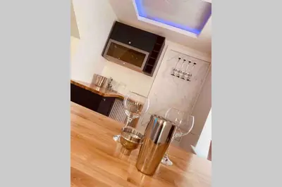 a kitchen with two wine glasses on a wooden table at The Hideaway - Farm Stay with hottub, pool table and outdoor cinema in Newmilns