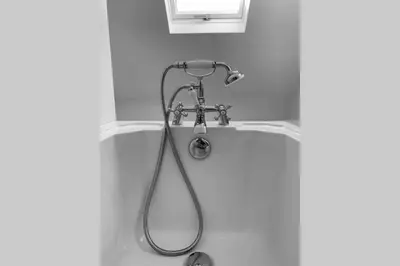 a bath tub with a shower in a bathroom at The Hideaway - Farm Stay with hottub, pool table and outdoor cinema in Newmilns