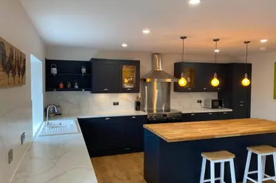 a kitchen with black cabinets and a counter top at The Hideaway - Farm Stay with hottub, pool table and outdoor cinema in Newmilns