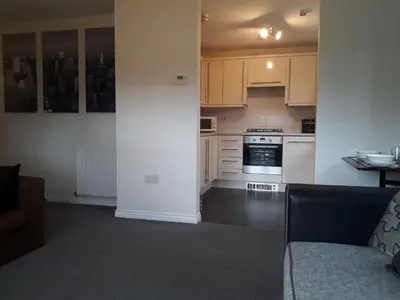 a kitchen with white cabinets and a couch in a room at Pond view in Airdrie