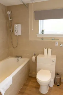 a bathroom with a toilet and a bath tub at Bachilton Farm Holidays in Perth