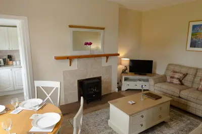 a living room with a fireplace and a couch and a table at Bachilton Farm Holidays in Perth
