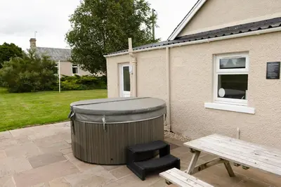 a trash can and a bench next to a house at Bachilton Farm Holidays in Perth