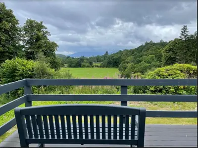 a bench sitting on a porch with a view of a field at Invernahyle Cottage in Acharra