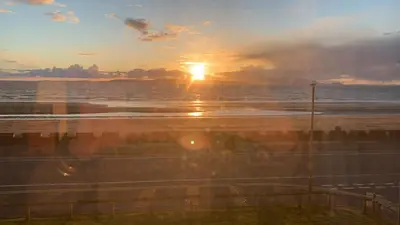 a sunset on the beach with the sun in the distance at Ayr Loft Apartment with Fabulous Views in Ayr