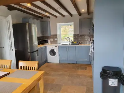 a kitchen with blue cabinets and a washer and dryer at Sea Otter Cottage in Appin