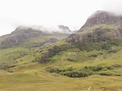 a misty mountain with green hills and trees at Sea Otter Cottage in Appin