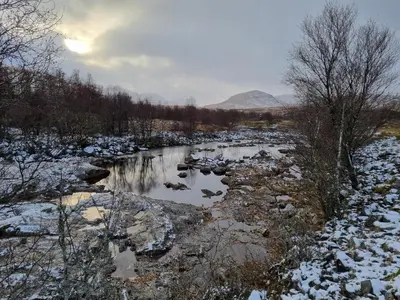 a river in the snow with a mountain in the background at Sea Otter Cottage in Appin