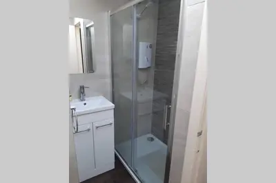 a bathroom with a glass shower and a sink at Cosy cottage with sea views close to local shops. in Lamlash