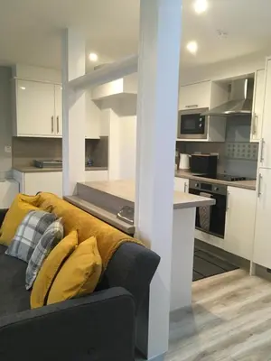 a living room with a couch and a kitchen at Cosy cottage with sea views close to local shops. in Lamlash