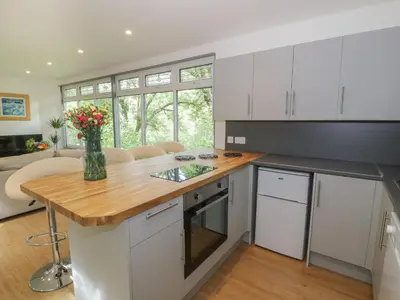 a kitchen with white cabinets and a wooden counter top at The River Lodge in Oban