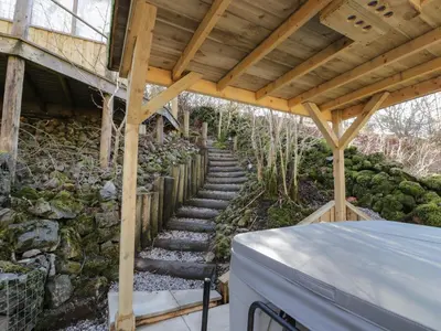a stone path leading to a house with a wooden roof at The River Lodge in Oban