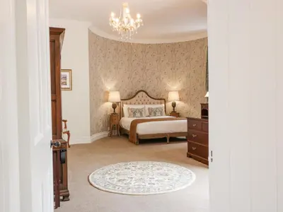 a bedroom with a bed and a chandelier at Brewhouse Flat - Culzean Castle in Maybole