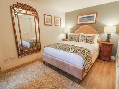 a bedroom with a bed with a mirror and a rug at The Coach House - Holmwood in Glasgow