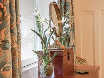 a mirror and a vase with flowers on a table at The Coach House - Holmwood in Glasgow