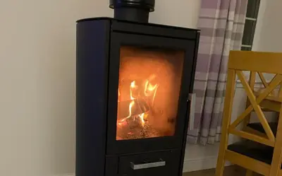 a black stove with a fire inside of it at 2-Bed Barn Hot Tub & Pet Friendly near Muirkirk in Cumnock